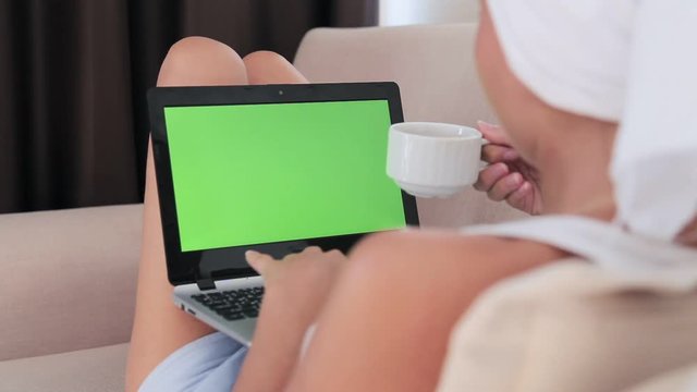 Beautiful woman looking at a laptop with green screen
