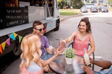 friends clinking bottles with drinks at food truck