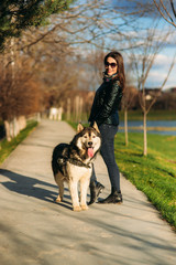 A girl is walking with a dog along the embankment. Beautiful husky dog. the river,