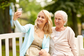 daughter and senior mother taking selfie at park