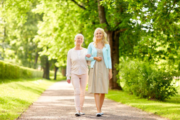 daughter with senior mother walking at summer park