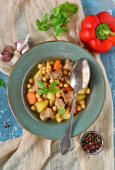 Homemade stew with potatoes, carrots and chickpeas on a blue background.