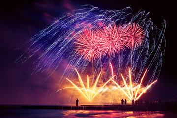 Beautiful, festive, colorful fireworks over the sea with reflection