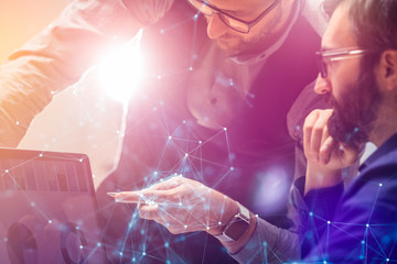 Two colleagues working on new global financial strategy analysis plan using laptop.Modern business team innovation concept.Project meeting at office with virtual graph and chart data interface