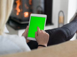 young woman using tablet computer in front of fireplace