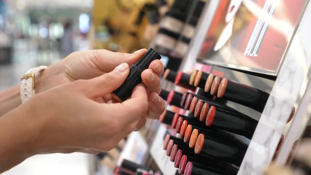 Closeup Of Female Hands Shopping For Lipstick In Beauty Care Store. 4K. 