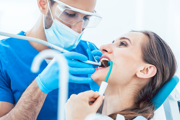 Young woman during painless oral treatment in the modern dental office of an experienced dentist