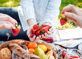 Young beautiful girls eating strawberries in the park