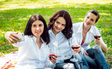 Young beautiful girls with glass of red wine in the park