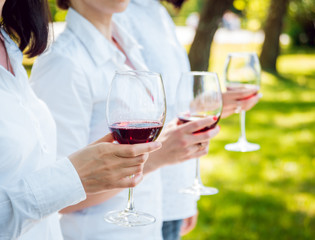 Young beautiful girls with glass of red wine in the park