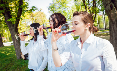 Young beautiful girls with glass of red wine in the park