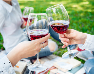 Young beautiful girls with glass of red wine in the park
