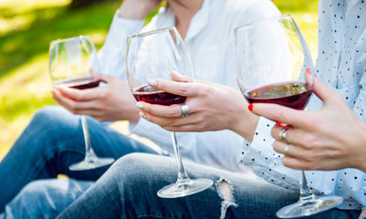 Young beautiful girls with glass of red wine in the park