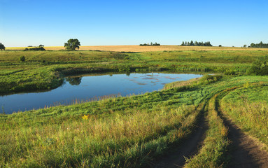 Fototapeta premium Sunny summer landscape.River Upa in Tula region,Russia.Ground country road in the meadows.