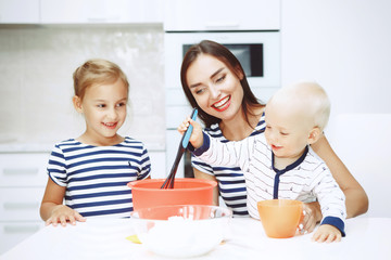Adorable happy family makes cakes together on your white kitchen.