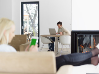young woman using tablet computer in front of fireplace