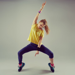 Portrait of active girl performing aerobics dance over grey background. Sport and leisure concept. 