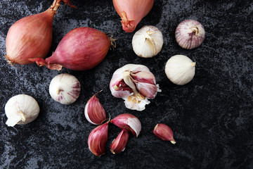 many garlic and onions vegetables on dark background.