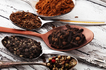 Various spices and spoons on white wooden table.