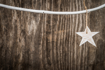 Cgristmas star hanging on branch over wooden background