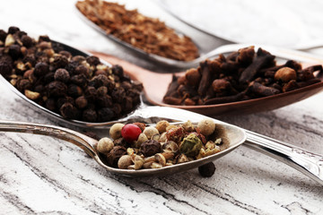 Various spices and spoons on white wooden table.