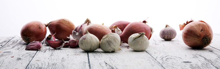 many garlic and onions vegetables on white wooden background.