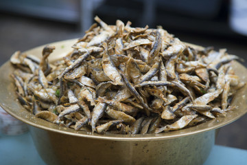 Crispy deep-fried small fish in a brass pot at the street market