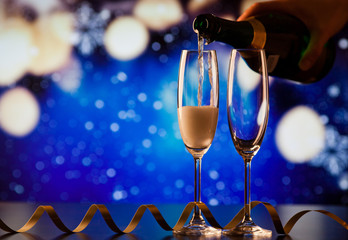 pouring champagne into glasses against holiday lights