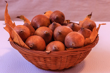 Ripe medlar and yellow leaves in wooden basket on white background