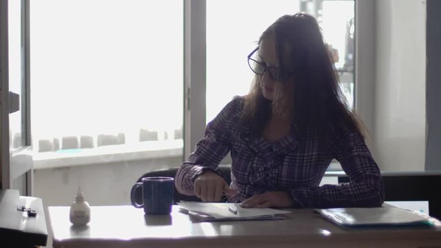 Businesswoman wearing eyeglasses working on laptop computer drinks coffee. Slow motion. 3840x2160