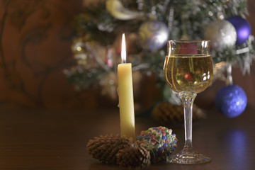 Crystal glass with white wine, Burning candle and Christmas tree