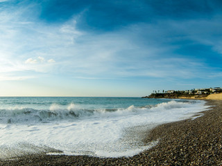 View of the beautiful sunset over the sea with wild pebble beach coast. Fisheye effect