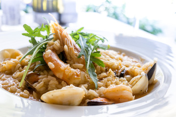 Tasty risotto with Shrimp, fresh herbs vegetables on a white plate