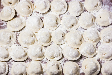Dumplings of hand-made meat, sprinkled with flour on the table.