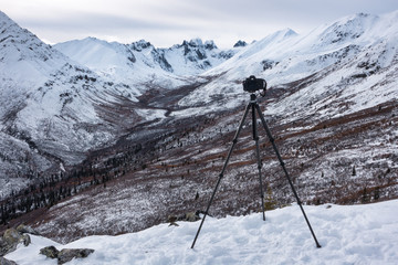 A DSLR camera on a tripod in front of a mountain view in the Yukon
