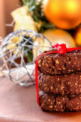 Stack of homemade healthy chocolate nuts oats cookies on wooden and fur-tree toys background. Christmas concept. Selective focus. Vertical.