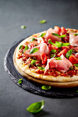 Pizza topped with black forest ham, capers and tomatoes