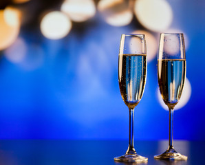 two champagne glasses against holiday lights and fireworks - new year celebration