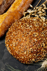 Rustic bread and wheat on dark background . Rural kitchen or bakery