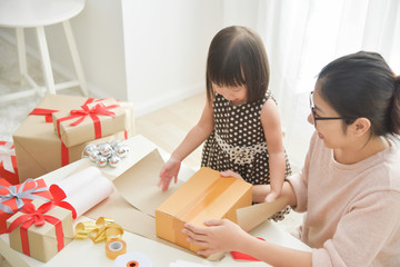 Young mother and her daughter wrapping a gift box.