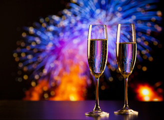 two champagne glasses against holiday lights and fireworks - new year celebration