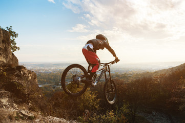 a young rider at the wheel of his mountain bike makes a trick in jumping on the springboard of the...