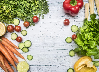 vegetable frame for vegetarian salad, fresh carrots, bell peppers, lime, cherry tomatoes, cucumbers, on a white rustic wooden background, space for text