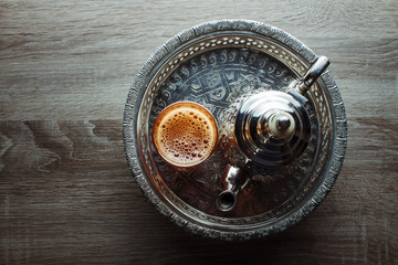 close up of moroccan traditional tea pot and glass on a silver plate - obrazy, fototapety, plakaty