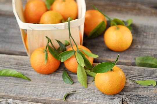 Fresh tasty tangerines with leaves on wooden table 