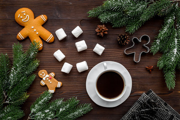 Coffee with gingebread cookies in christmas evening. Cup near spruce branch on dark wooden background top view
