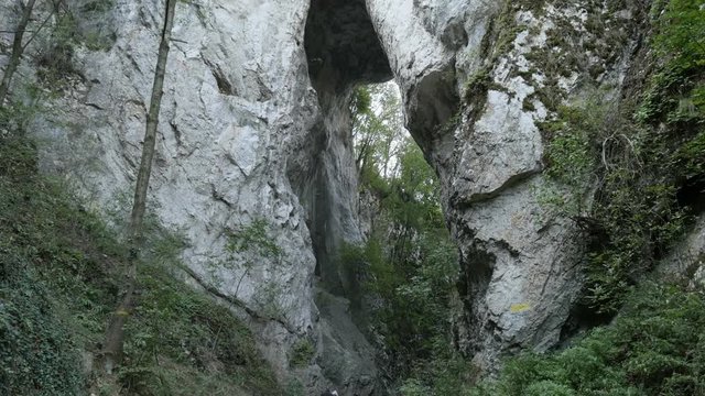 Hikers under natural stone bridge slow tilt footage - Beautiful nature in Eastern Serbia