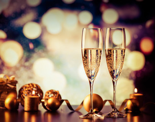 two champagne glasses against holiday lights and fireworks - new year celebration