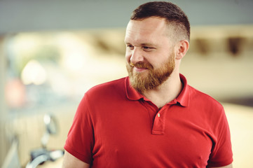  man with a red beard, dressed in a red gaiety in the city. Happy and healthy. looks and mysteriously smiles. Concept idea of success