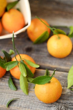 Fresh tasty tangerines with leaves on wooden table 